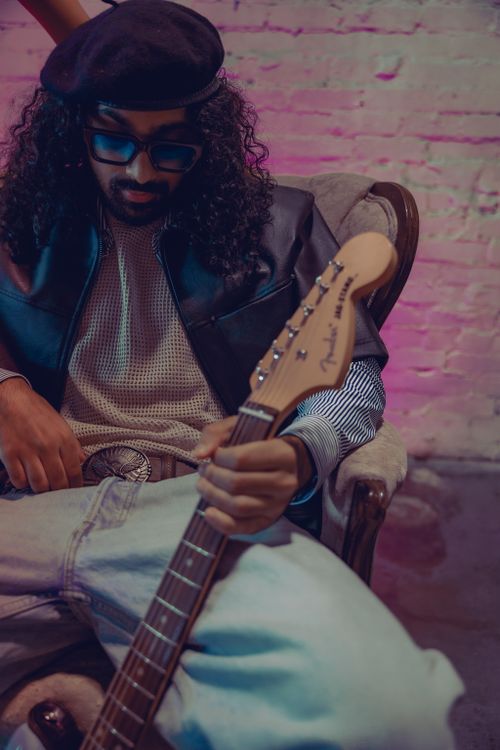 Free A trendy musician in a cool setting playing a guitar, showcasing style and mood. Stock Photo