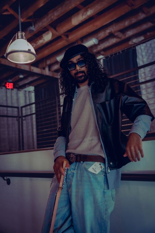 Free A fashionable man with sunglasses and leather jacket poses confidently indoors, capturing urban style. Stock Photo