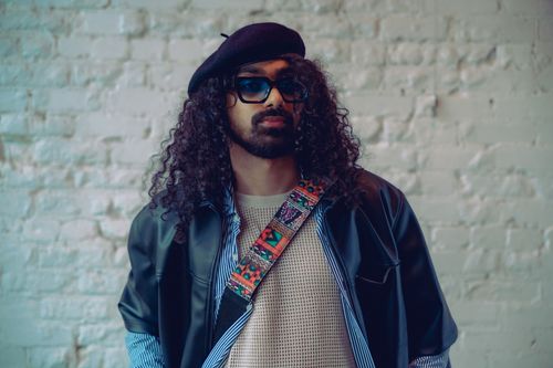 Free A fashionable musician in sunglasses and a beret poses against a brick wall. Stock Photo