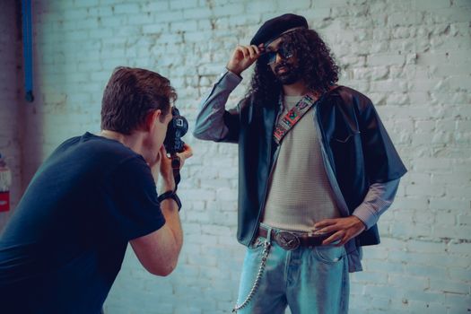 A photographer captures a stylish model posing with sunglasses indoors.
