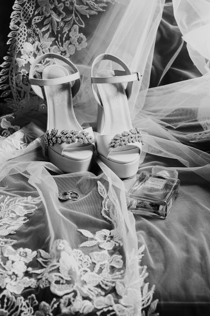Stylish wedding shoes with floral lace detailing, surrounded by bridal accessories in black and white.