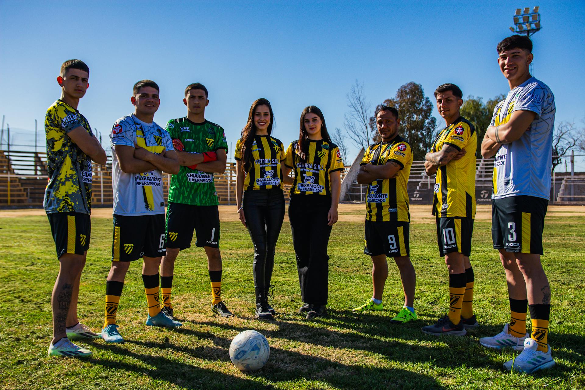 Seven athletes in football gear team photo on sunny field