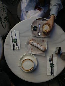 Overhead view of coffee and pastry on a marble cafe table, perfect for breakfast settings.