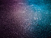 特写镜头捕捉了纹理表面上的水滴，在粉红与蓝色渐变灯光下显得充满活力