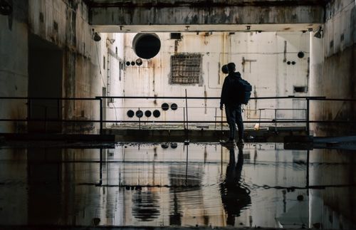 Free Silhouetted figure in an abandoned industrial space with water reflections, capturing urban exploration. Stock Photo