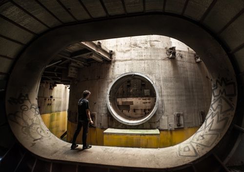 Free A person exploring an industrial-looking, abandoned urban tunnel with graffiti. Stock Photo