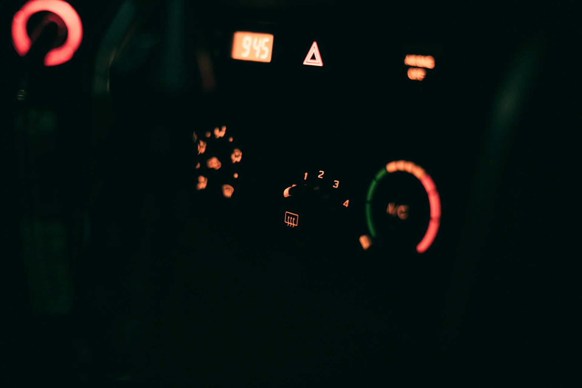 A car dashboard with glowing dials and controls, showcasing illuminated technology at night.