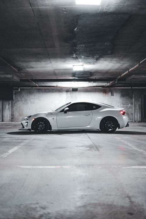 Free A sleek white sports car parked in a dimly lit underground garage, showcasing modern design. Stock Photo