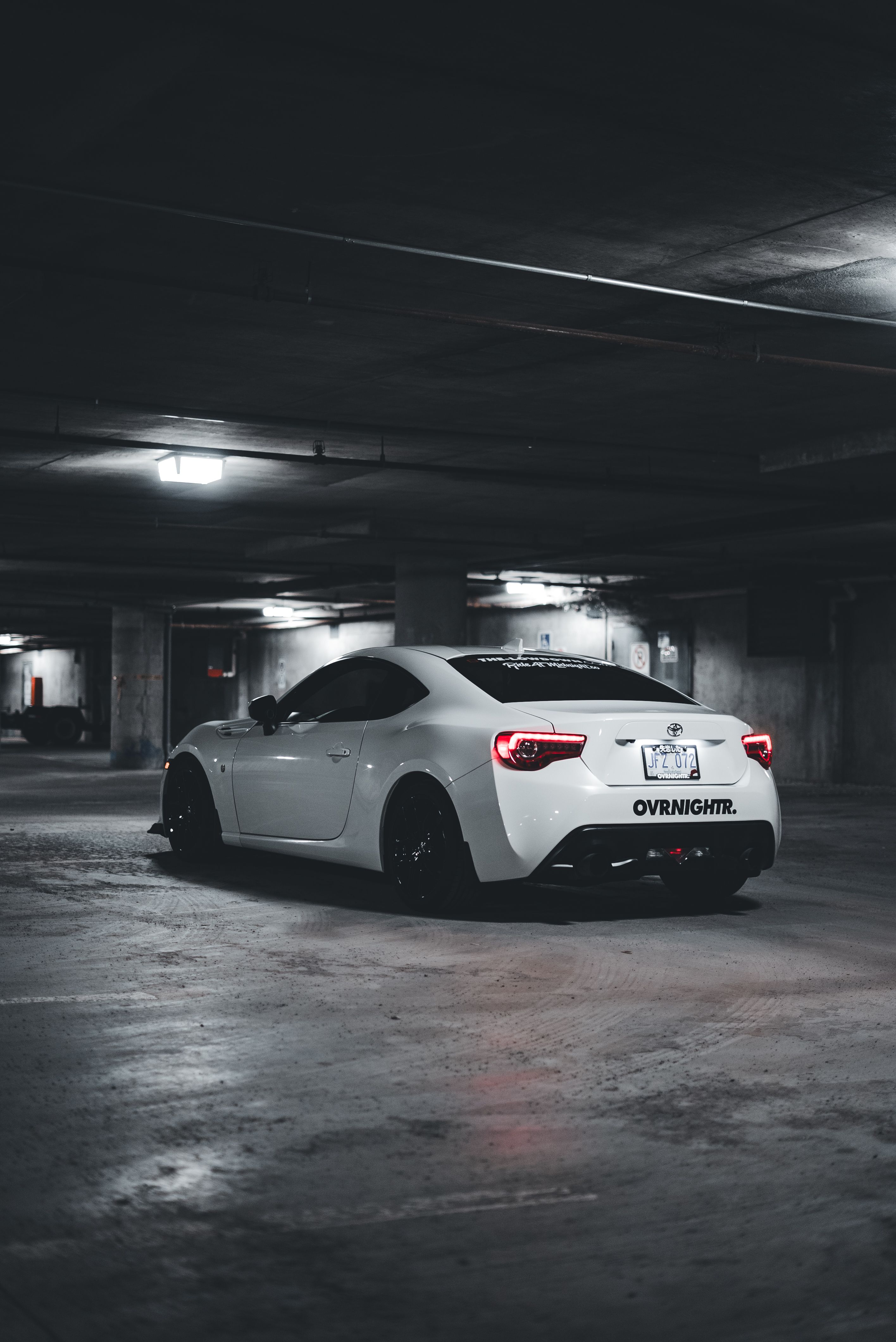 A sleek white car parked in a dimly lit underground garage, showcasing modern design and elegance.