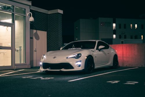Free Sleek white sports car parked in a city lot at night, showcasing modern design and style. Stock Photo