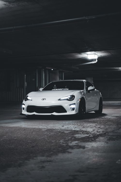 Free A white sports car parked in an underground garage with dramatic lighting. Stock Photo