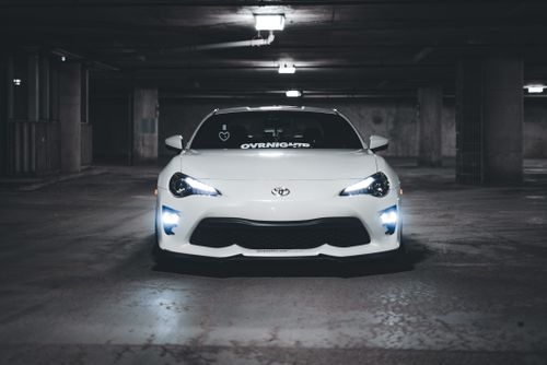 Free A stylish white car parked in a dimly lit underground garage. Stock Photo