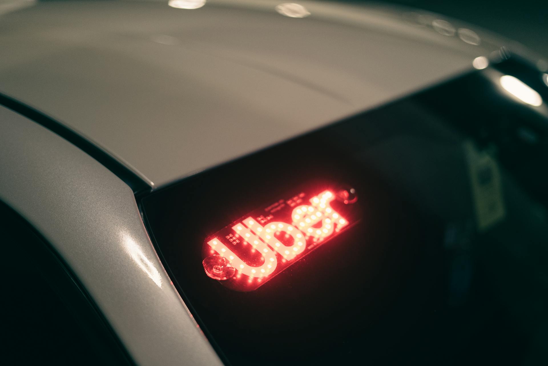 Close-up of a ride-sharing car with a bright red illuminated sign for night-time travel.