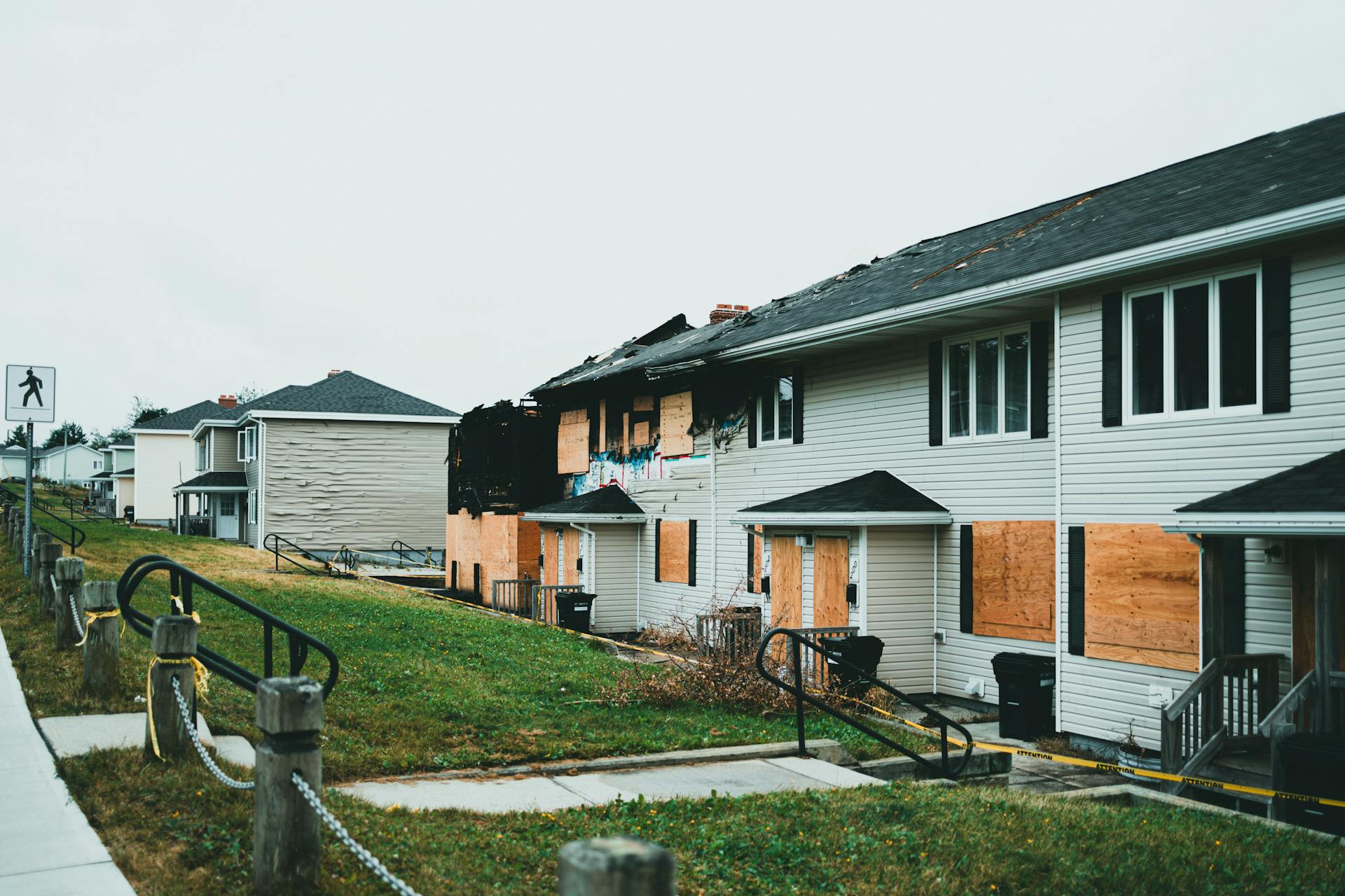 Boarded-up suburban homes with visible fire damage and neglect.