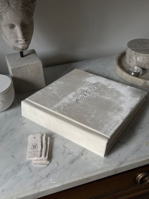 Free A white photo album elegantly displayed on a marble countertop with decorative elements. Stock Photo