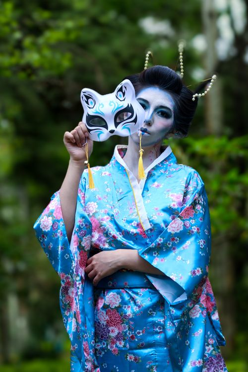 Free A woman in a vibrant blue kimono holds a traditional mask, portraying cultural elegance. Stock Photo
