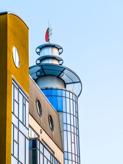 Free Contemporary building featuring a distinctive glass tower and colorful facade. Stock Photo