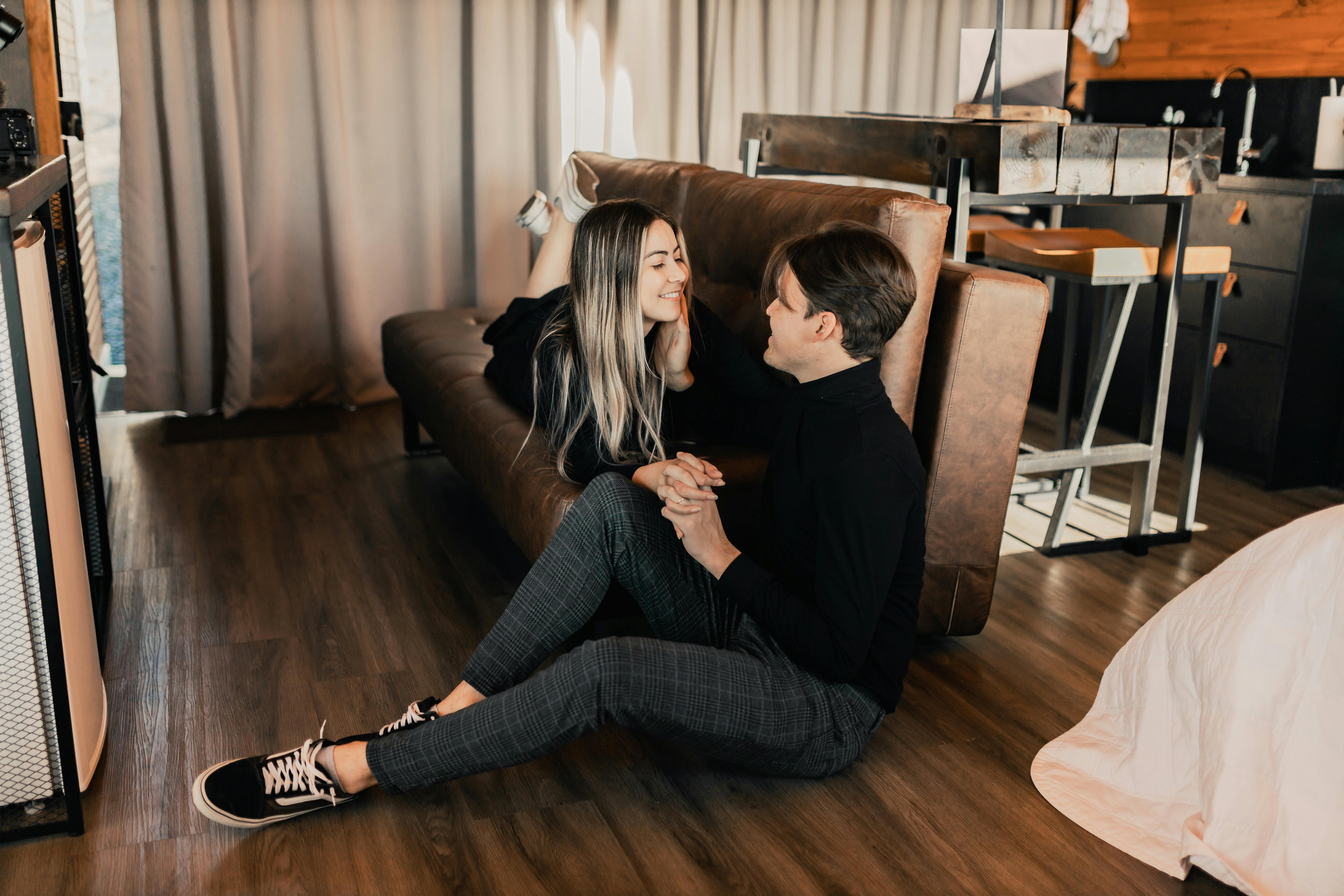 a couple sitting on the floor in front of a couch