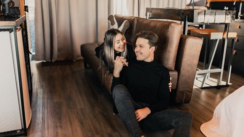 A joyful couple sharing a tender moment on the floor by the sofa in a cozy living room.