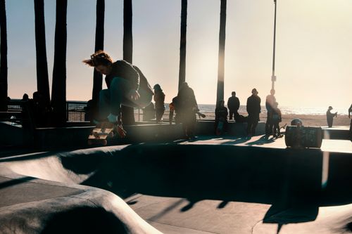 Free A skateboarder performs an aerial trick at Venice Beach Skate Park during sunset. Stock Photo