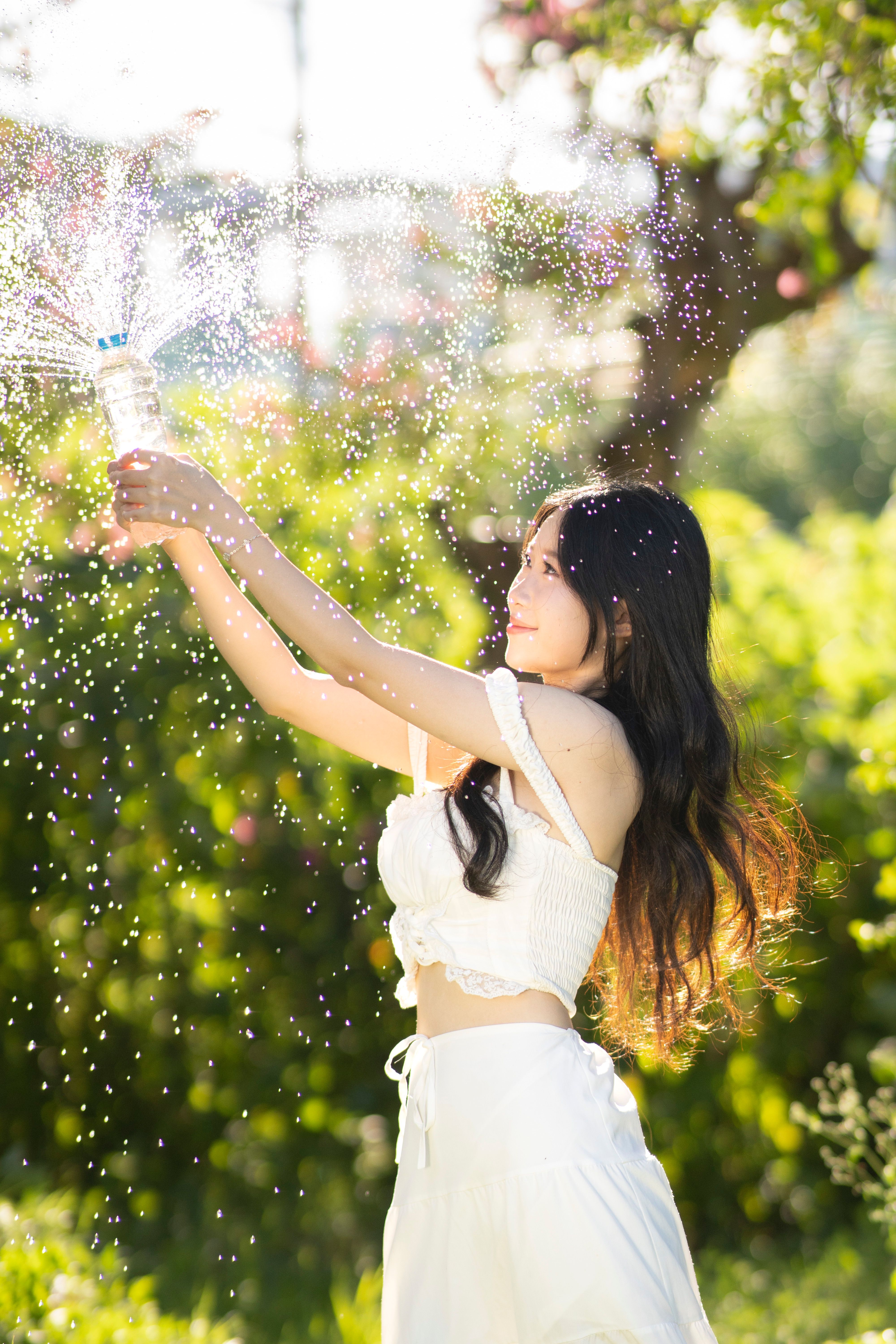 Smiling Woman Holding Sprinkling Bottle of Water · Free Stock Photo