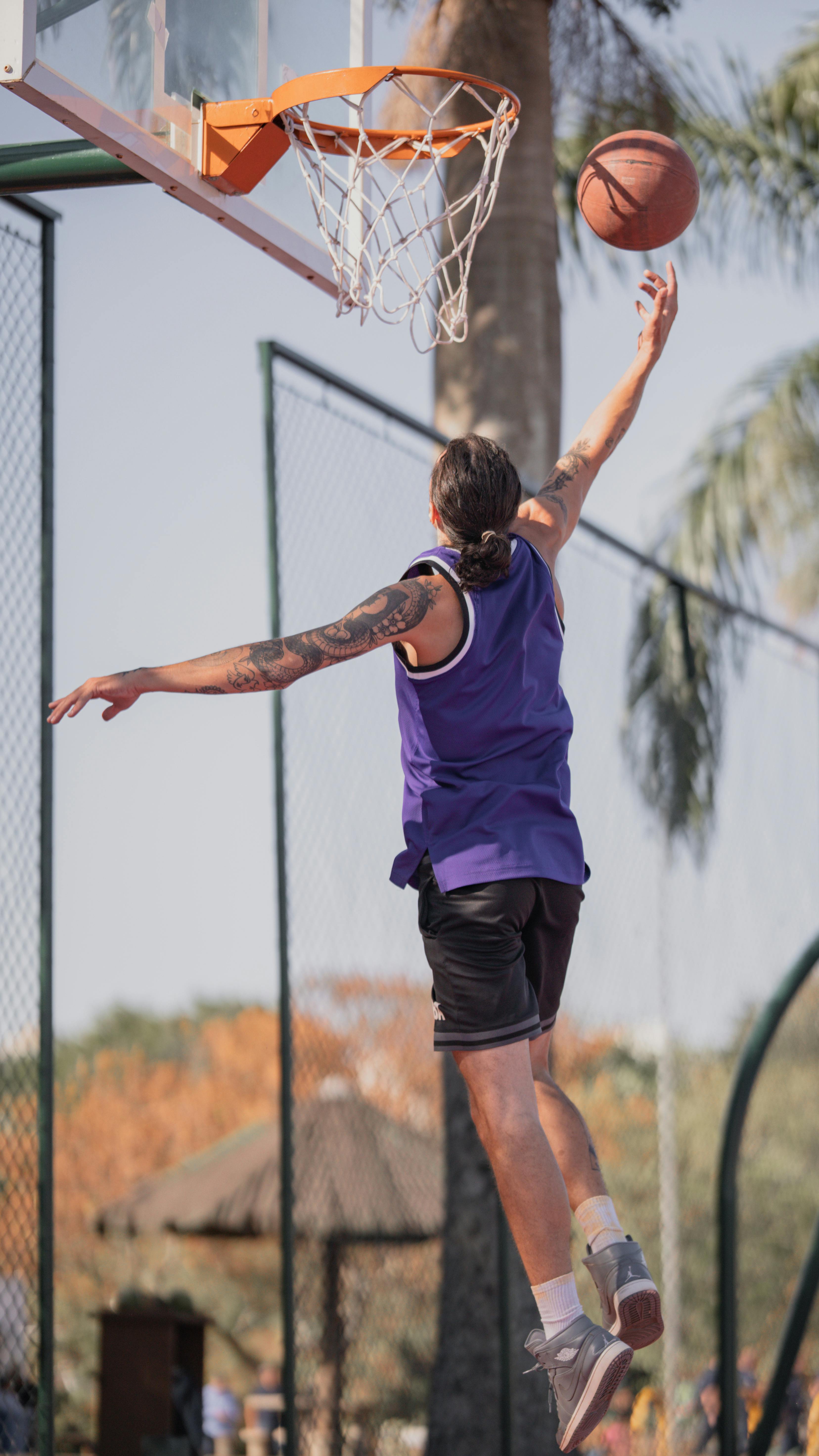 a man in purple shirt is dunking a basketball