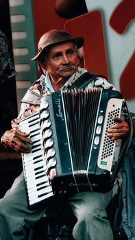 An elderly man skillfully plays the accordion, infusing the street with nostalgic melodies.
