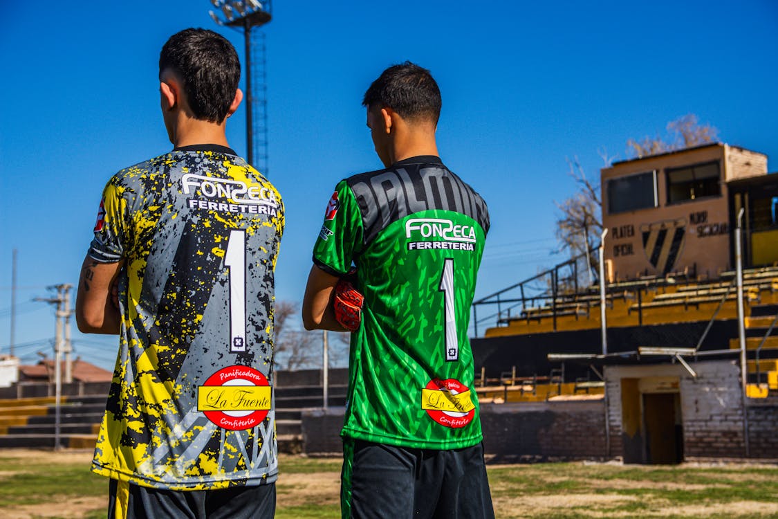 Two soccer players in green and yellow jerseys · Free Stock Photo