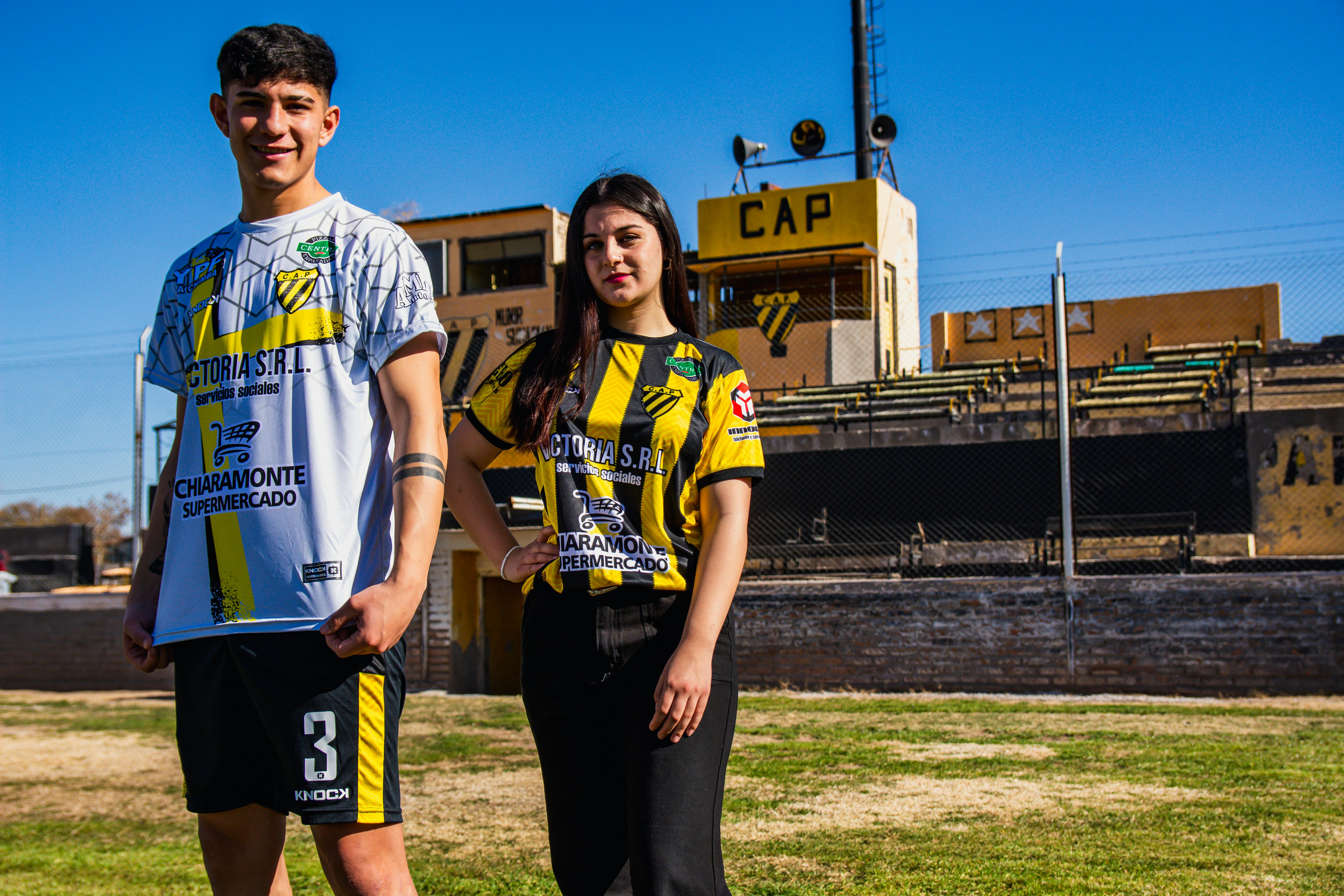 Two people standing in front of a soccer field