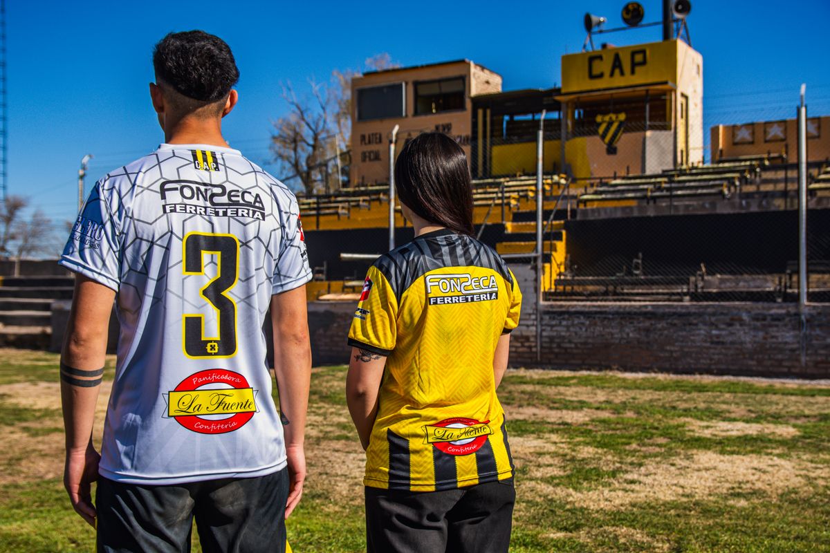 Two sports fans wearing team jerseys at the CAP stadium on a sunny day.