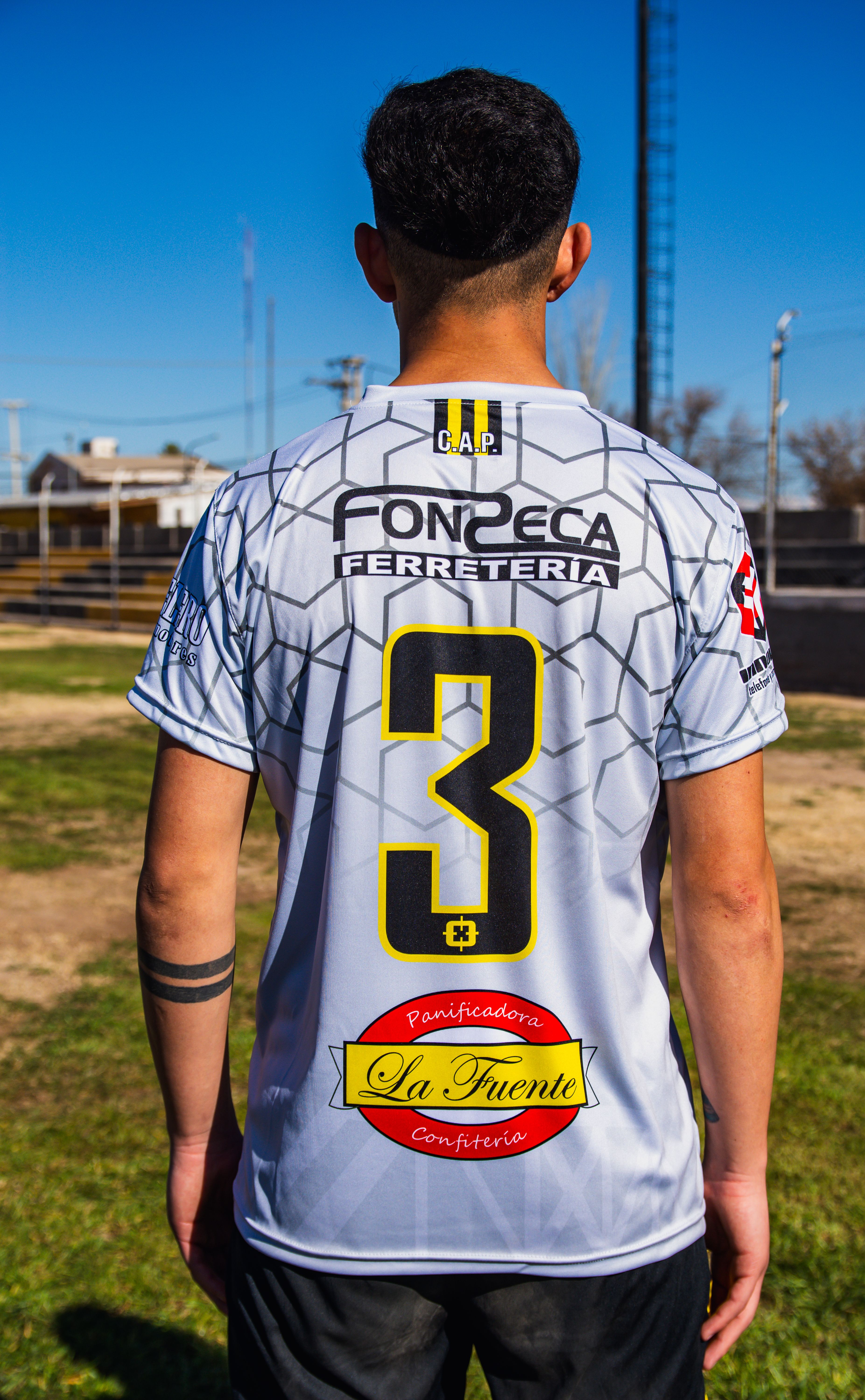Soccer player standing on field wearing jersey number three on a sunny day.