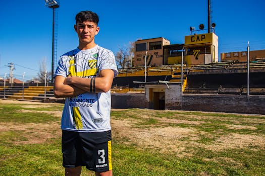 Confident young soccer player posing on the field during a bright day.