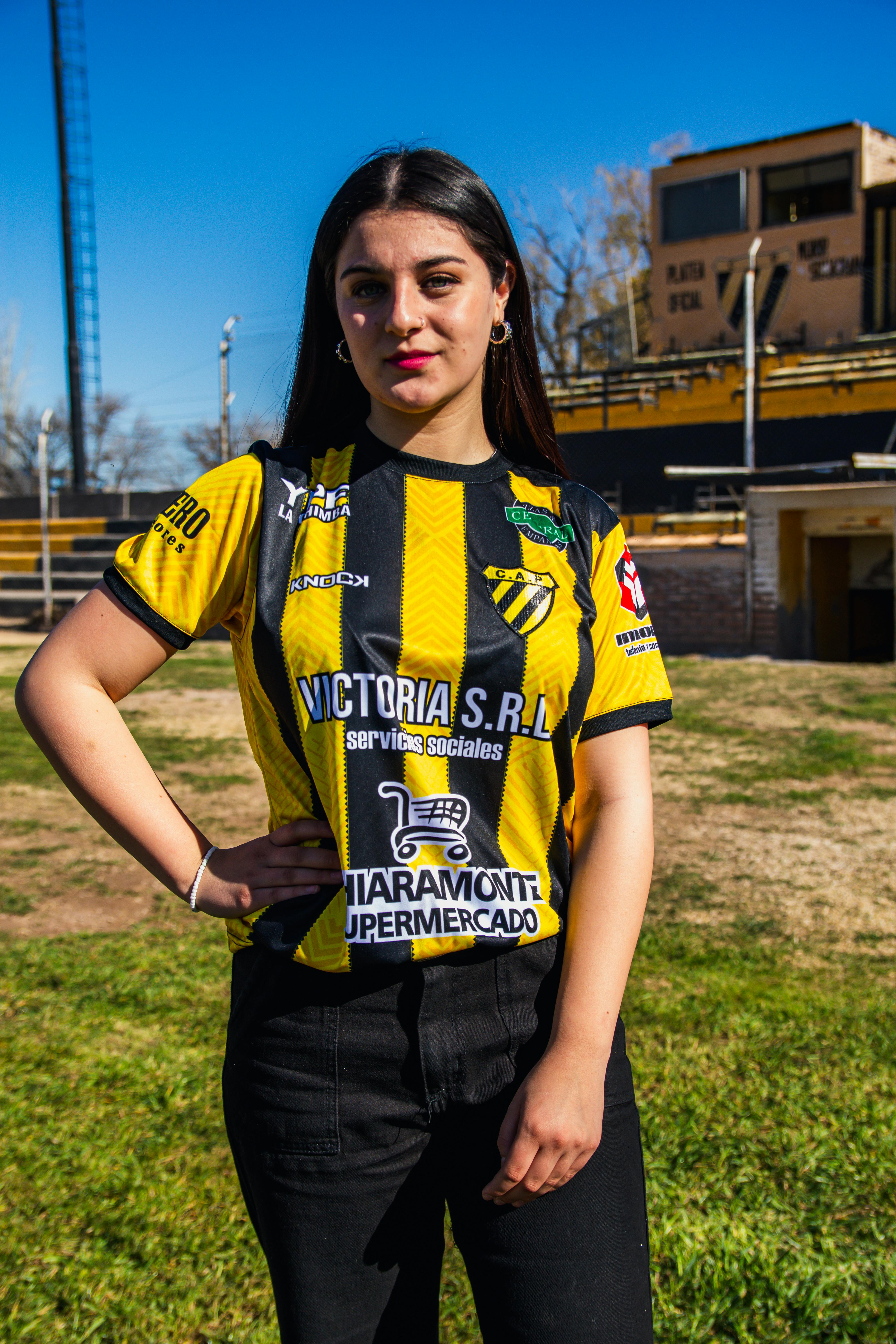 Portrait of a young woman wearing a sports jersey standing outdoors at a stadium.