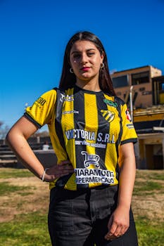 Portrait of a young woman in a sports jersey standing outdoors with a confident expression.