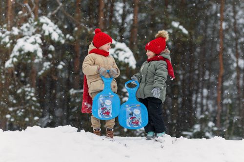 Free Two kids in winter attire holding sleds, enjoying a snowy day outdoors. Stock Photo