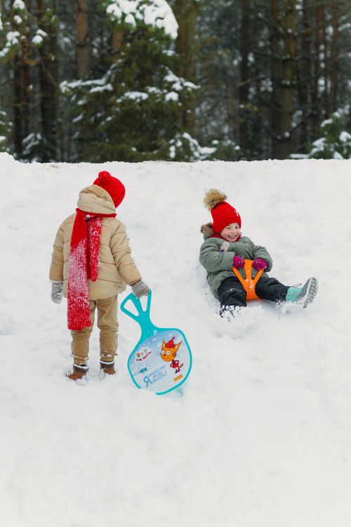 Free Two children having fun sledging in the snowy outdoor winter forest. Stock Photo