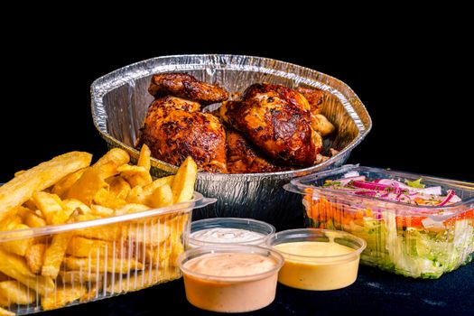 Savor a complete rotisserie chicken dinner with crispy fries, fresh salad, and dipping sauces.