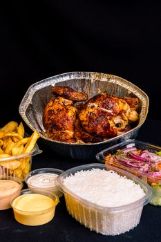 A mouthwatering rotisserie chicken served with rice, fries, and fresh salad, perfect for a hearty meal.