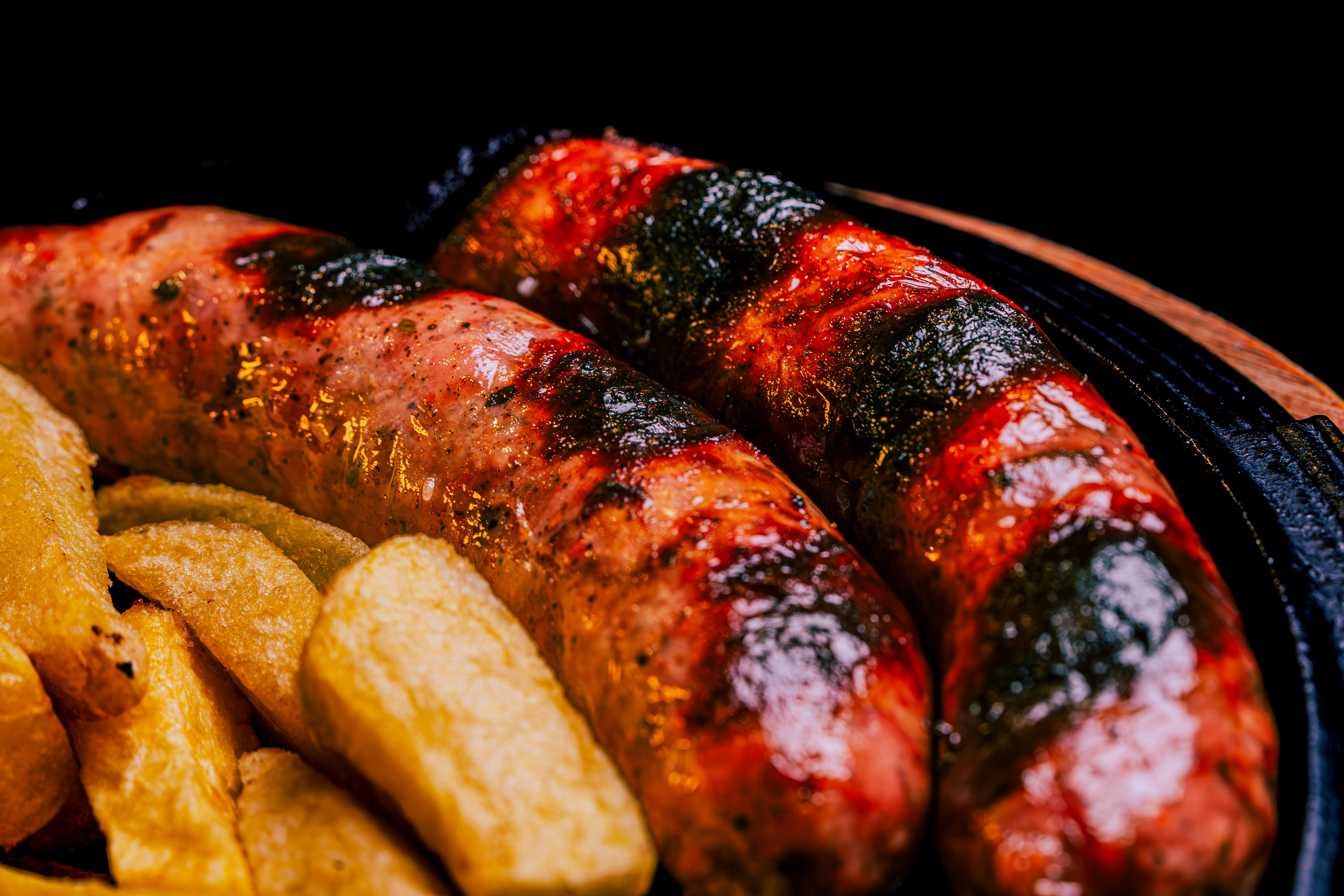 two sausages and potato wedges on a plate