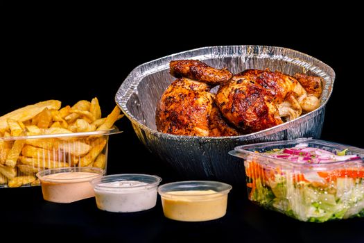 Savory roasted chicken served with fries, salad, and sauces for a flavorful meal.