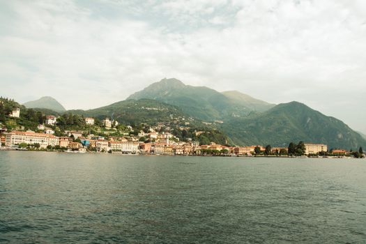 A picturesque view of Bellano village by Lake Como in Lombardy, Italy, surrounded by lush hills.