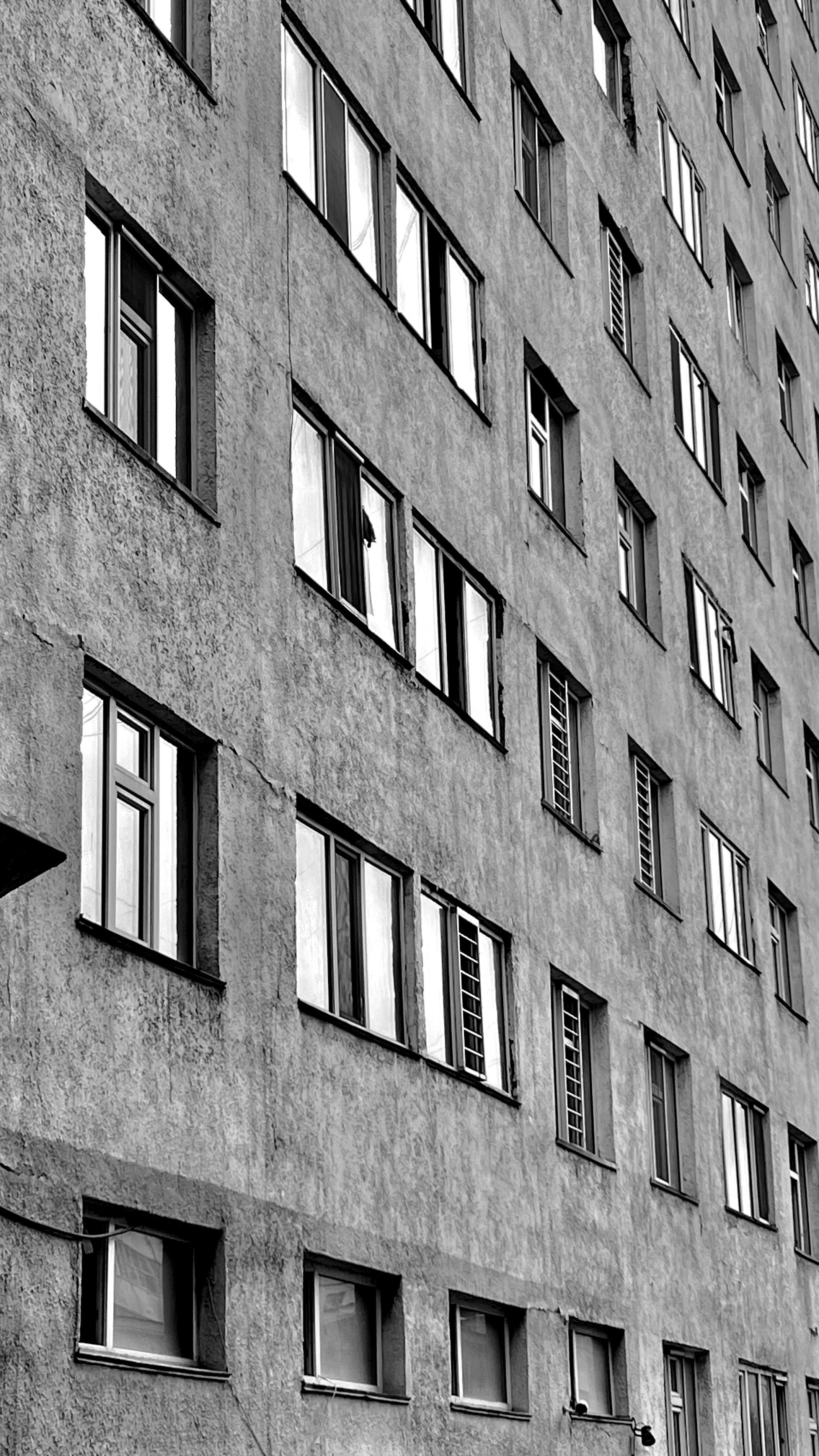 Fotomural Foto en blanco y negro de la fachada geométrica de un edificio de apartamentos urbano con ventanas.