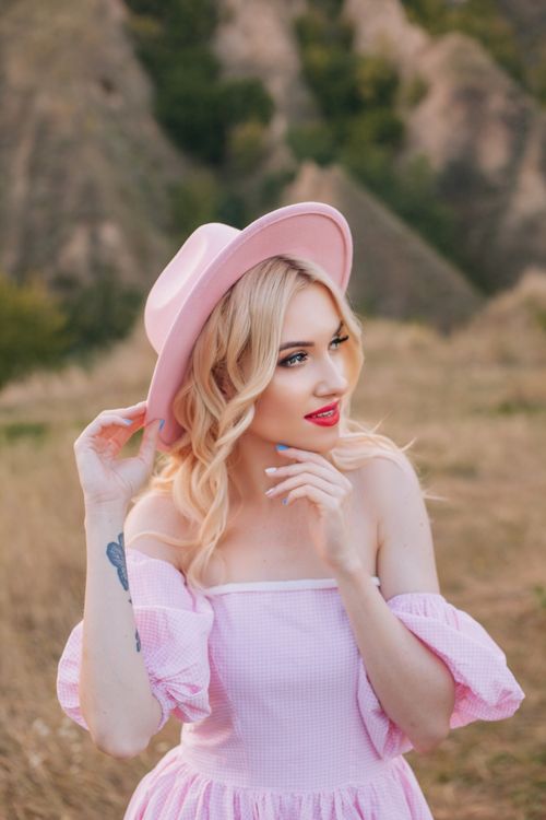 Free A fashionable woman enjoys the outdoors in a pink dress and hat. Stock Photo