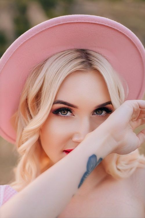 Free Portrait of a young woman in a pink hat with delicate makeup, exuding elegance and style. Stock Photo