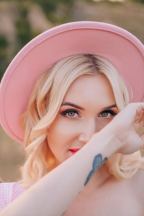 Free Close-up portrait of a stylish woman in a pink hat posing outdoors. Stock Photo