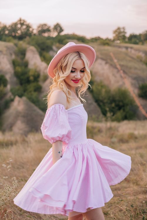 Free Blonde woman in a pink dress enjoying a sunny day outdoors with a natural background. Stock Photo
