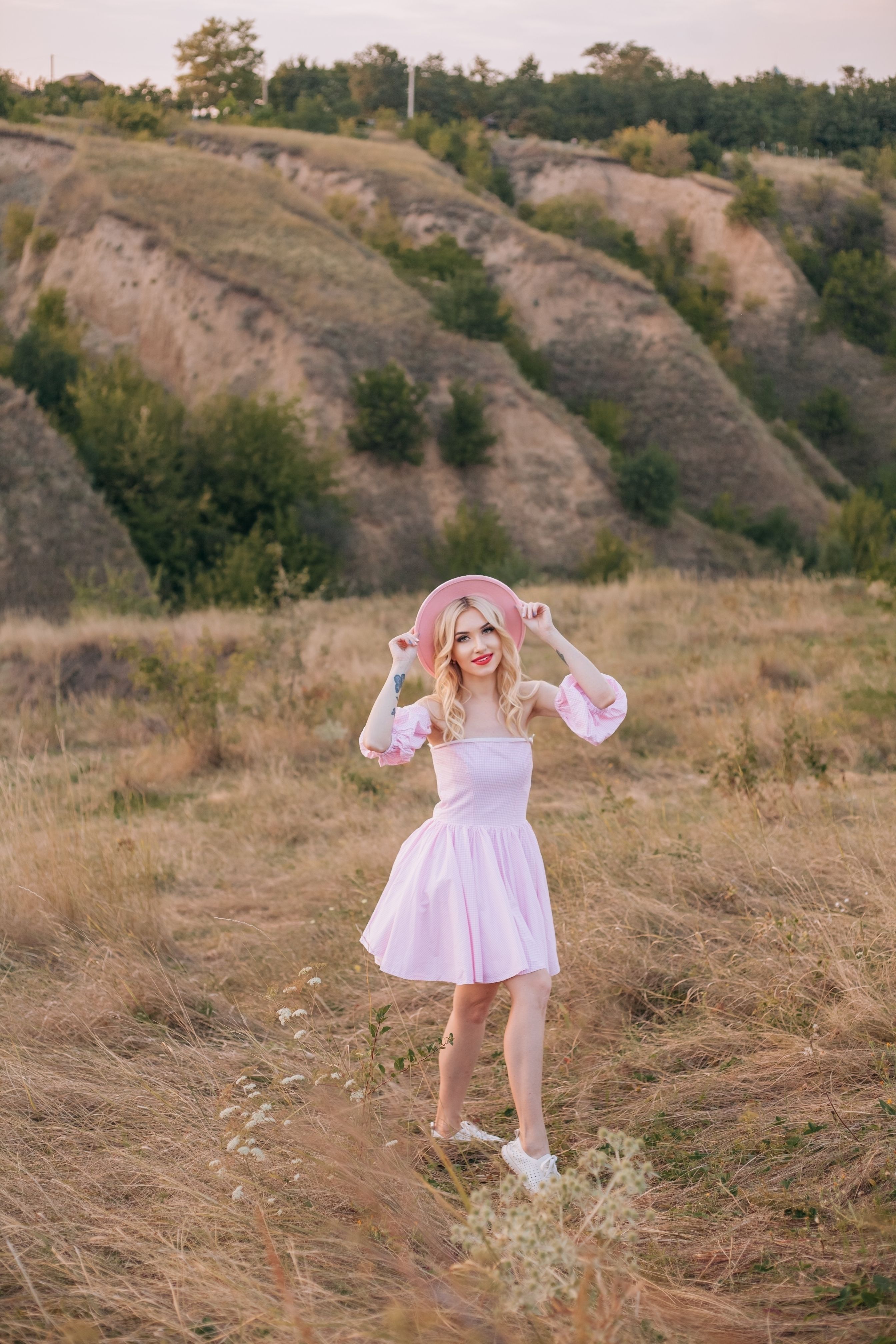 A woman in a pink dress and hat is standing in a field · Free Stock Photo