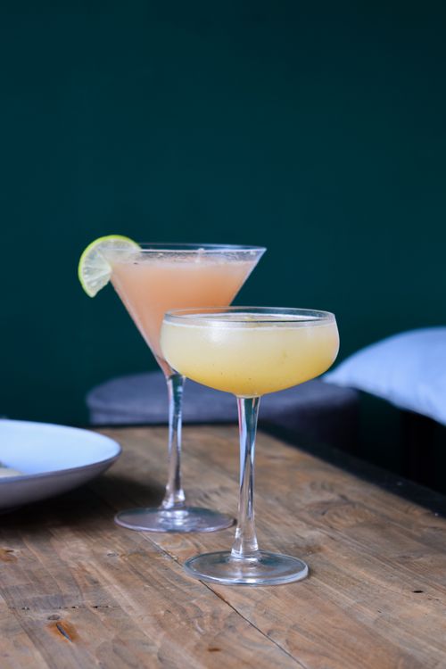 Free Two refreshing cocktails in elegant glasses with lime garnish on a rustic wooden table. Stock Photo