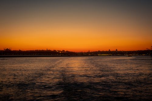 Free Serene sunset view of a city skyline reflecting in a calm river's water. Stock Photo