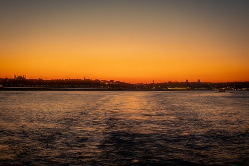 Free Captivating sunset over water with a city skyline and lights reflecting on the surface. Perfect for travel themes. Stock Photo